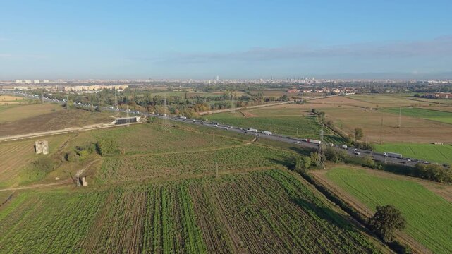 Traffic Congestion Aerial View: An aerial perspective captures a vast expanse of countryside marred by significant traffic congestion on a distant highway.