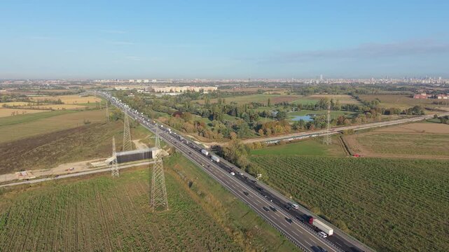 Aerial view highway traffic alongside a passenger railway in Milan, Italy. The scene illustrates interconnected road and rail infrastructure relevant to logistics planning