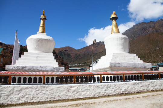 Stupas stand side by side in a mountain village under a clear sky