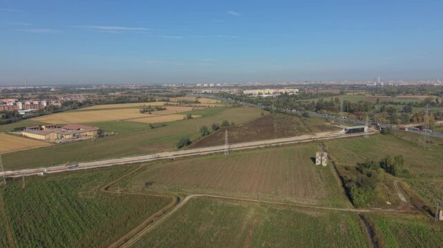 Aerial View of Rural Landscape with Train Tracks: An expansive drone perspective captures the sprawling countryside, featuring agricultural fields, a winding road.