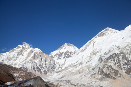Snow-covered peaks rise under a clear blue sky in the Himalayas on a sunny day during winter