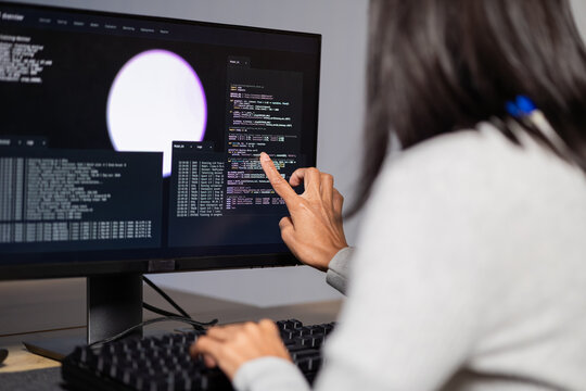 Computer Programmer moves fingers toward computer display beside keyboard, connecting screen review with practical office computer software work, illustrating individual development work.