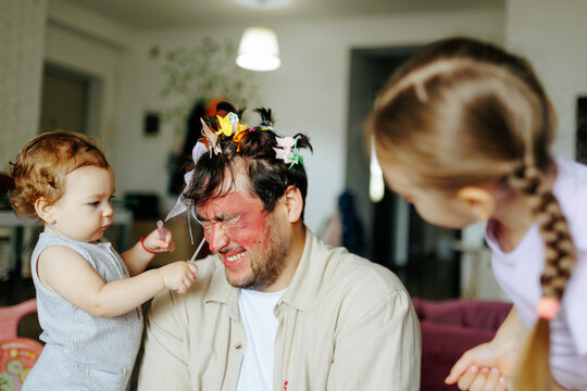 Funny dad making hilarious facial expressions after messy makeup. Playful parenting and humor