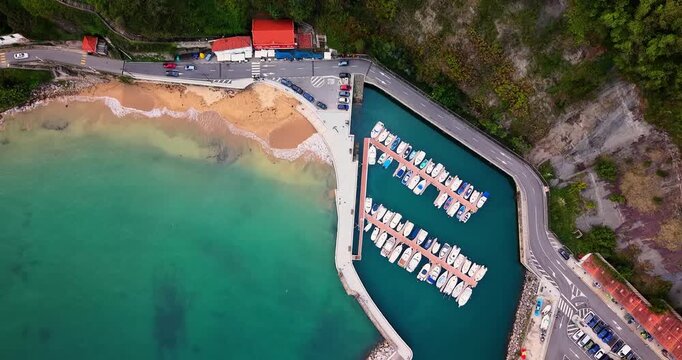 Lastres (Llastres) port aerial top-down drone shot of marina docks, breakwater jetty, and sandy beach in Asturias, Spain