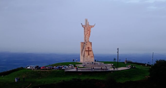 Oviedo Sacred Heart monument aerial drone panning shot at dusk revealing illuminated Christ statue on Mount Naranco peak, Asturias, Northern Spain.