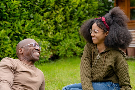 father and teenage daughter laughing together in a garden on a sunny day