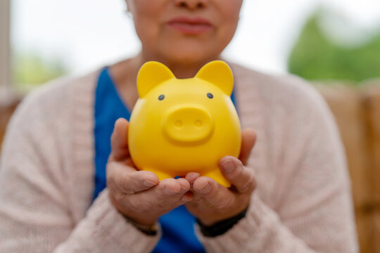 Person holding yellow piggy bank in hands indoors in a cozy setting