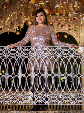 Woman in Elegant Dress Posing at a Festive Christmas Gazebo at Night