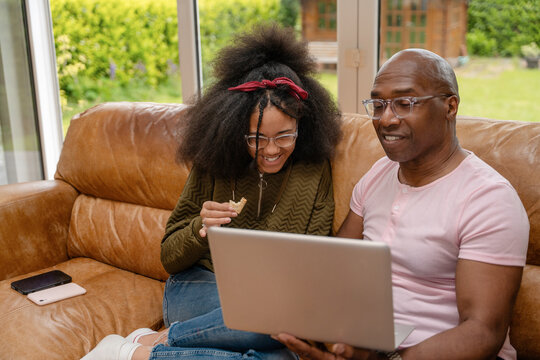 Family members share a moment together while using a laptop on a couch in a living room