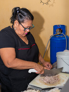 Woman Cutting Meat on a Plastic Board at a Mexican Taco Stand