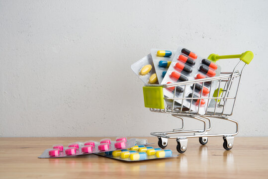 Healthcare, medical, buying medicine in drugstore or medical insurance concept. Pharmaceuticals medicine pills and capsules pack in shopping trolley on wooden table with white background copy space.