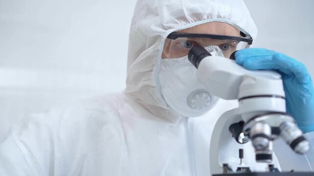 Scientist in ppe analyzing samples using a microscope in a laboratory setting