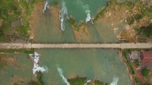 Aerial top down view of river flowing under a bridge in vietnam