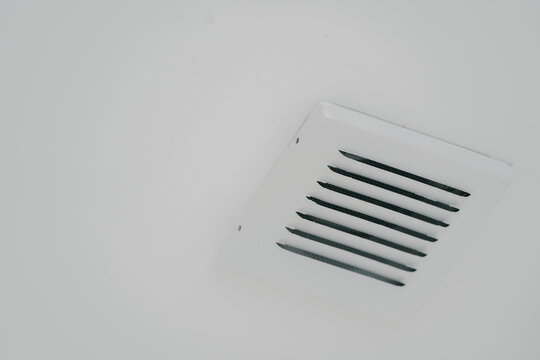 Ceiling vent exhaust air conditioning ventilation square grille mounted on plain white interior surface feels peaceful and clean minimalism