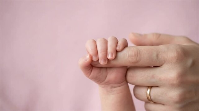 Newborn baby holding an adult finger in close-up. Parent and infant bonding. Family love, care and connection. Early childhood, parenting and newborn concept. Copy space.