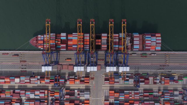Aerial top view of container ship unloading cargo at port terminal