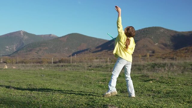 Girl, play, field, young child jumps for joy while playing with a retro tether ball toy outdoors in sunny mountain landscape