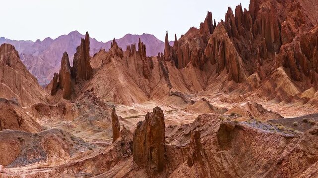 Aerial view of a dramatic red rock canyon with jagged sandstone pinnacles and arid mountain terrain in the Red Mountain Stone Forest, Kuqa, Xinjiang, China