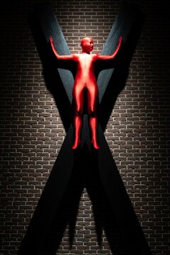 A person in a red bodysuit standing against a large black X on a brick