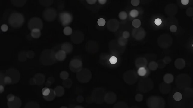 Intentionally blurred soft monochrome bokeh lights drift across a dark abstract field. Cinematic title, luxury branding, and dramatic transition.