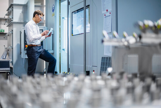 The engineer inspects the production machinery with a tablet