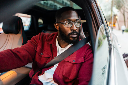 Man driving a modern car in an urban setting wearing seatbelt
