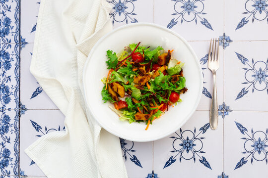 A vegan lemon chicken salad sits in a bowl on patterned tiles