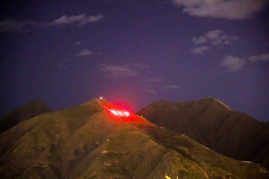 Red-lit slogan reading &ldquo;Long live China&rdquo; glows on a dark mountain near Lhasa at night, a stark symbol of Beijing&rsquo;s political control and propaganda over Tibet, July 2025