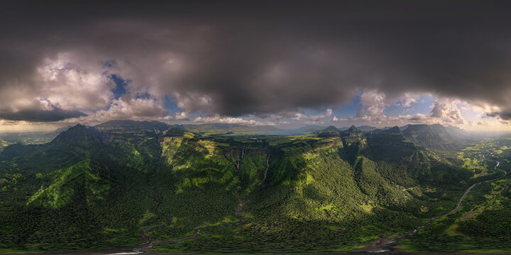Aerial view of Kalu Waterfall cascading down the lush green mountains of the Western Ghats under a dramatic cloudy sky in Khireshwar, Maharashtra, India.