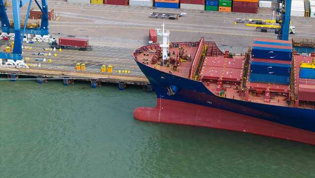 Aerial view of the Port of Felixstowe with a large container ship docked at the quay, colorful shipping containers, and industrial cranes, Felixstowe, England, United Kingdom.