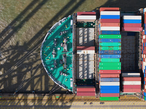 Aerial view of the Port of Felixstowe showing the bow of a large container ship loaded with colorful shipping containers docked at the terminal Felixstowe, England, United Kingdom.