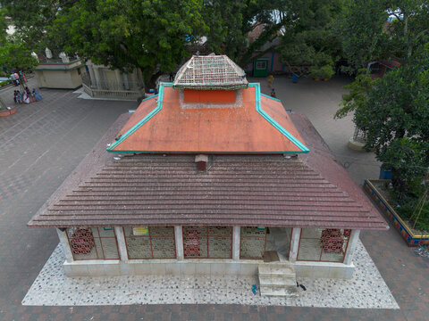 Aerial view of Sri Sri Loknath Baba Mondir with its distinctive orange tiered roof, surrounded by a paved courtyard and lush green trees in Narayanganj, Dhaka, Bangladesh.