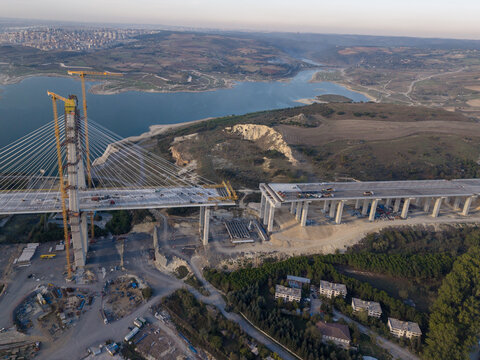 Aerial view of a large cable-stayed bridge under construction with tall cranes and concrete pillars spanning across a reservoir in Istanbul, Istanbul, Turkiye.