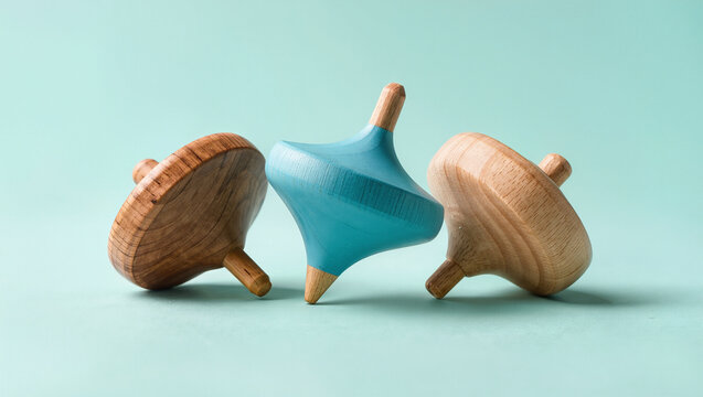 three wooden spinning tops tilted at different angles on a mint green surface, soft studio light with gentle shadows, conceptual balance and instability and work life harmony concept