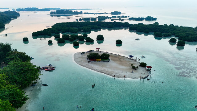 Aerial view of Pasir Perawan Beach with a small sandy island, clear turquoise water, and lush mangroves in Kecamatan Kepulauan Seribu Selatan, Daerah Khusus Ibukota, Indonesia.