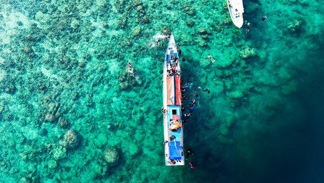 Aerial view of Pari island with a boat full of tourists snorkeling in the clear turquoise water, South Kepulauan Seribu, Jakarta, Indonesia.