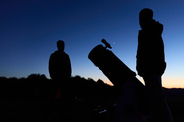 Amateur astronomers observing stars, planets, Moon and other celestial objects with a telescope in nature. © astrosystem