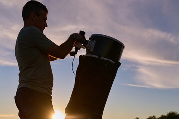 Amateur astronomer preparing and collimating telescope during sunset for night observations of stars, Milky Way, Moon and Planets. © astrosystem