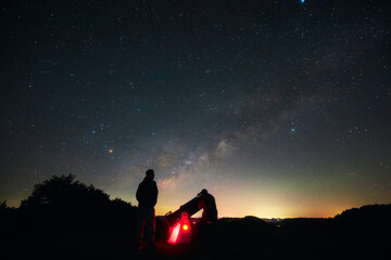 Amateur astronomers observing stars, planets, Moon and other celestial objects with a telescope in nature. © astrosystem
