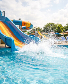 Colorful water slide splashing into a clear blue pool on a sunny day  