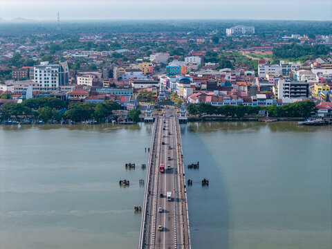 Jambatan Muar Johor bridge spans wide river, linking town across water. City sprawls beneath soft haze