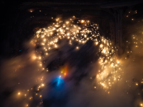 Fire burn swirl through dark, smoky air. Single blue glow anchors the chaos below