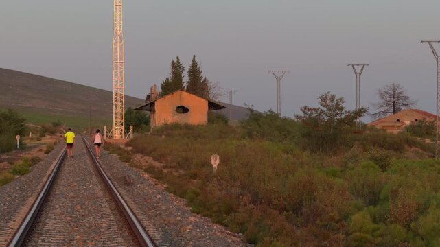 Couple Walking Along Railway Track in Hazy Rural Sunset