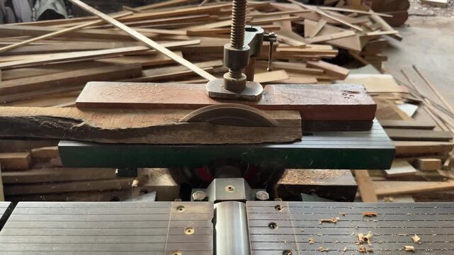 Horizontal front view of carpenter cutting wooden plank on table circular saw in workshop