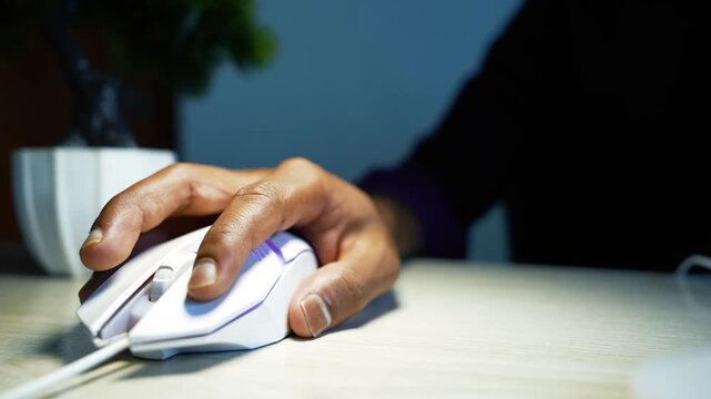 Hand using a computer mouse at a desk, Close-up of a hand using a white computer mouse on a desk, representing office work, technology, internet browsing, and everyday computer use.