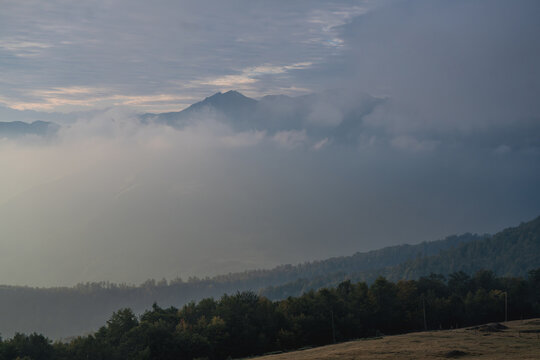 Golden hour light over misty mountain ranges and dark mountain slopes