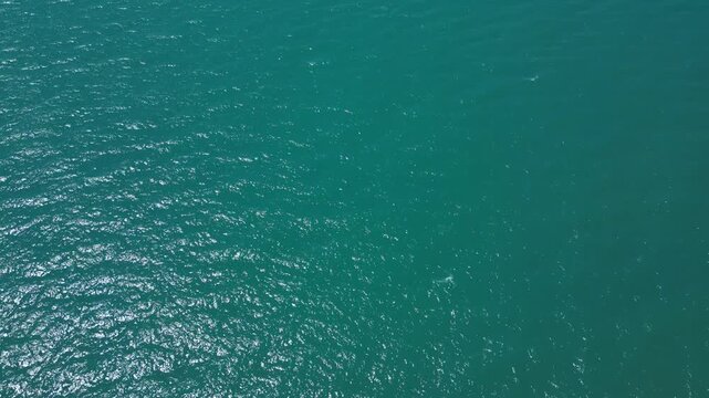 Aerial Top Down View of Turquoise Sea Water Surface with Sun Glare
