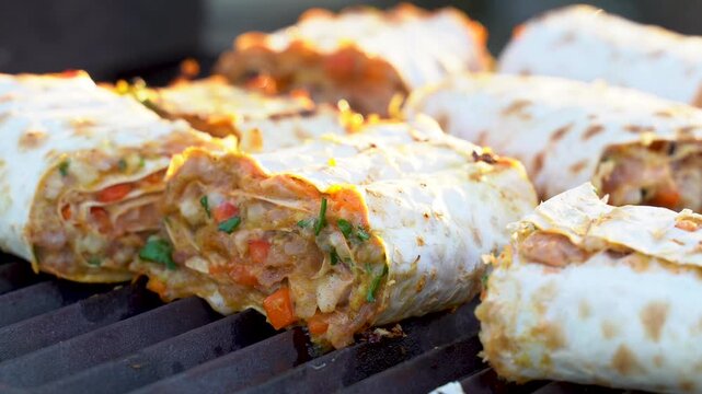 Sizzling lavash is grilled to perfection, stuffed with flavorful minced meat and vibrant vegetables. Watch as each roll captures mouthwatering goodness on the grill.