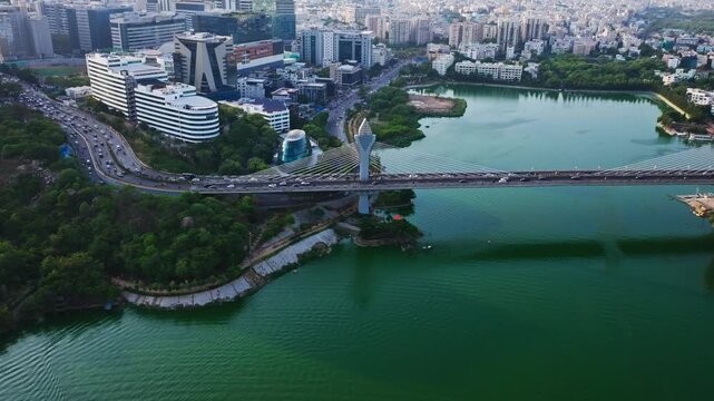 Traffic flow on cable bridge with durgam cheruvu, Oval Building, Inorbit Mall, apartments and ITC Kohenur at madhapur, hyderabad, telangana, india. day time, trucking shot, drone shot, 4k.
