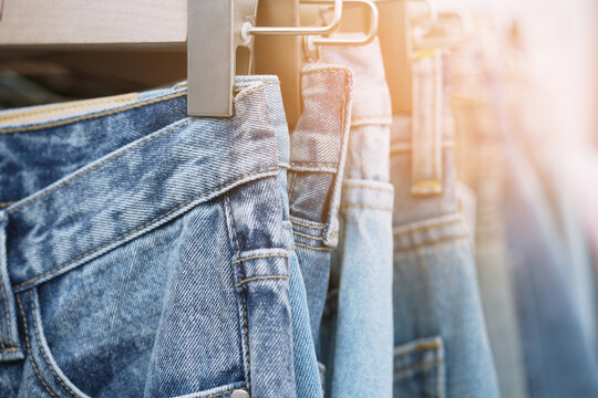 A close up of a blue denim row of jeans hanging on a rack. of different colors and styles. Concept of variety and choice.	